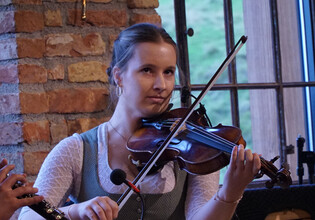 Nahaufnahme einer Musikerin mit Geige in traditioneller Kleidung. | © Hans Fuchs