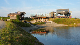 Panoramablick auf den Speicherteich am Asitz in Leogang mit Abendsonne, Konzertbühne auf einer Glasplattform und der Bergstation der Muldenbahn | © Gerald Weiskopf