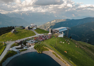 Blick auf das Open-Air-Konzert der TONspuren am Asitz mit Bergstationen, Speichersee und Bergpanorama in Leogang. | © Michael Geißler 